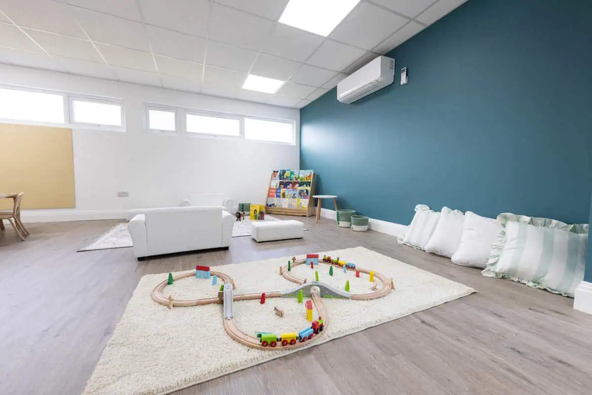 Bright and spacious nursery playroom with toys and soft seating for children.
