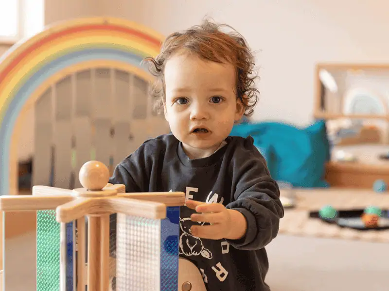 Monkey Puzzle Day Nursery Kingston Child Young child playing with wooden toys at Monkey Puzzle Kingston nursery.